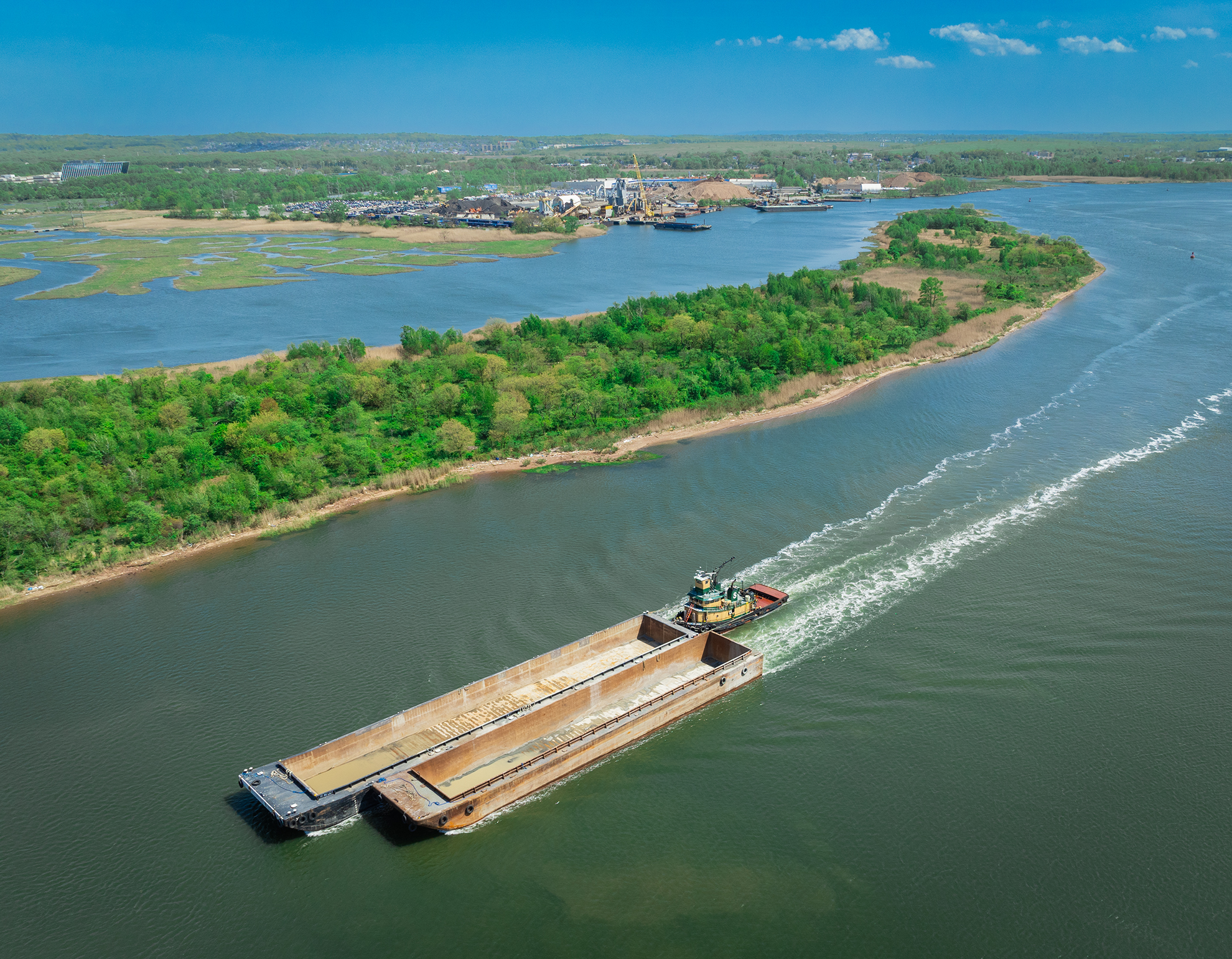 Drone Photograph of a Yellow & Green tug boat pushing two empty sand barges going up the Arthur Kill Waterway in New Jersey