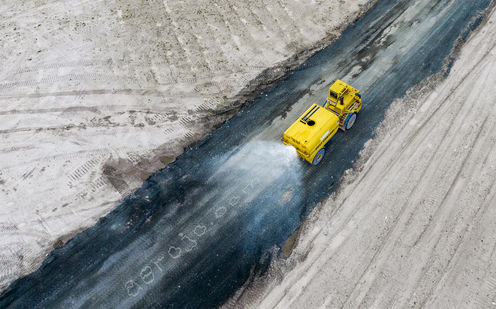 Drone photo of water truck wetting dirt road on a construction site